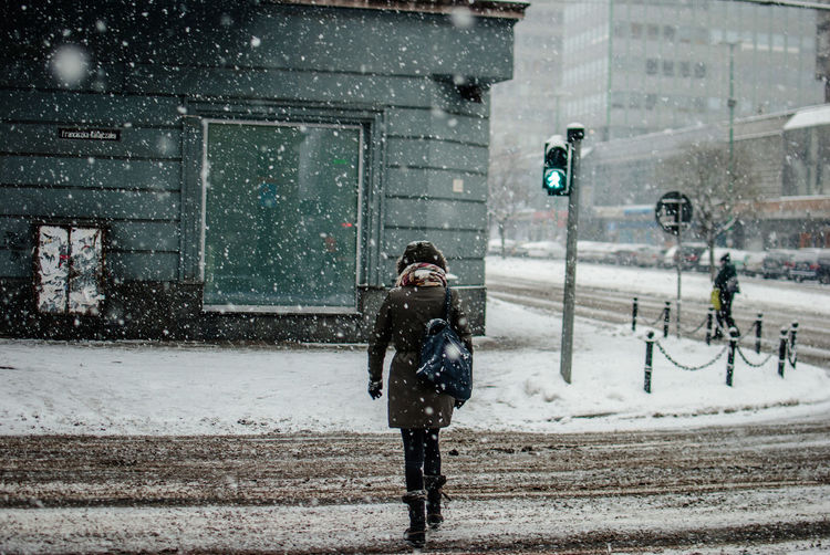 Rear view of woman crossing street during winter