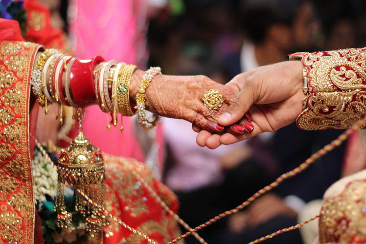 Cropped image of bride holding groom hands in ceremony