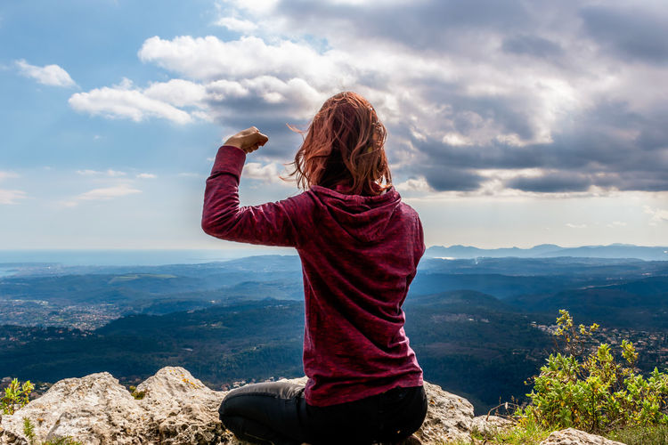 Rear view of woman looking at mountains against sky