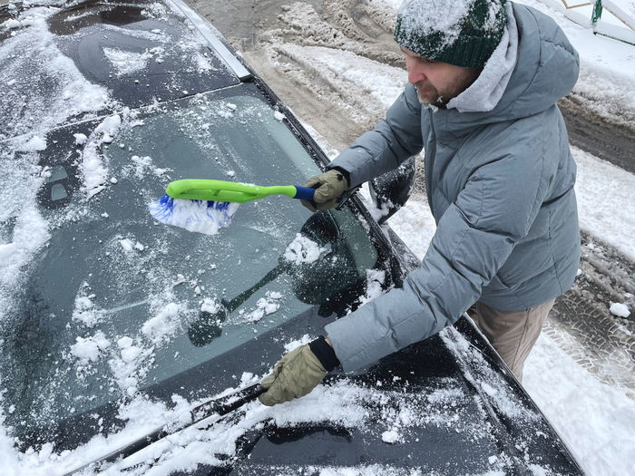 Man cleaning snowy car