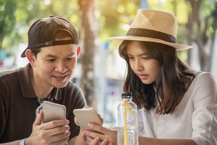 Smiling couple holding smart phone sitting at restaurant