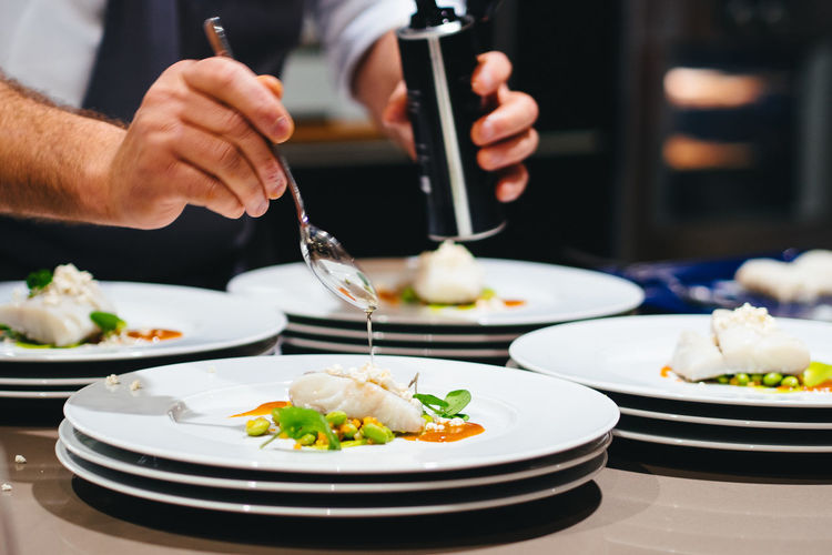 Cropped image of chef preparing seafood in plate at restaurant