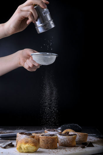 Cropped image of man dusting powdered sugar on dessert in kitchen