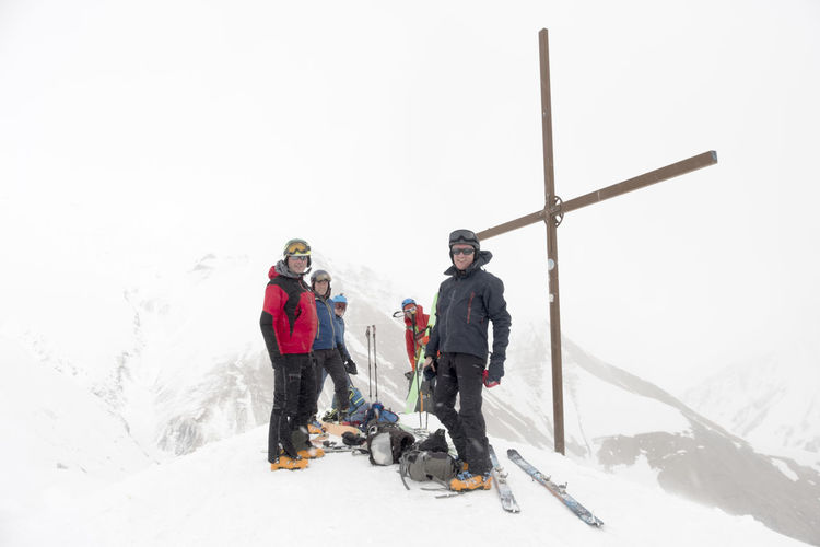 Georgia, caucasus, gudauri, peeope at summit cross on a ski tour