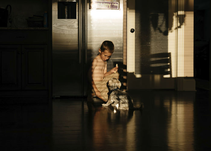 Boy looking at dog while sitting on floor