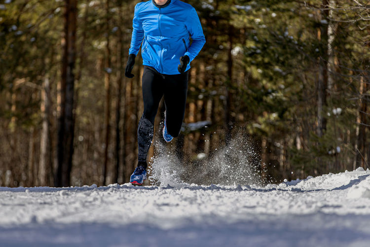 Male athlete running on snowy trail in woods