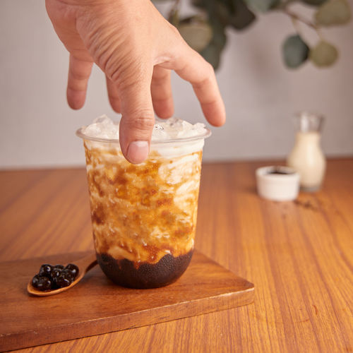 Midsection of person holding ice cream on table