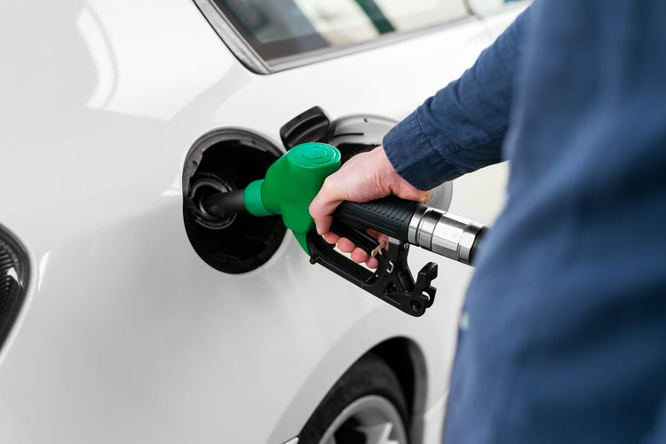 Cropped unrecognizable man refilling vehicle tank at petrol station during energy crisis