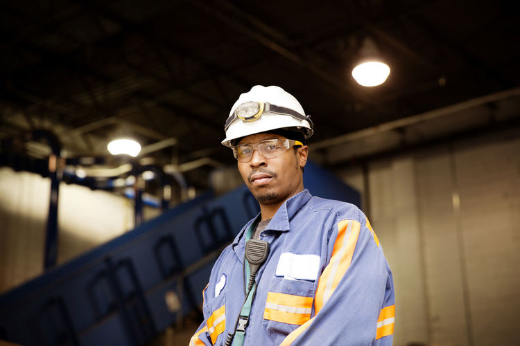 Portrait of male worker standing in illuminated recycling plant