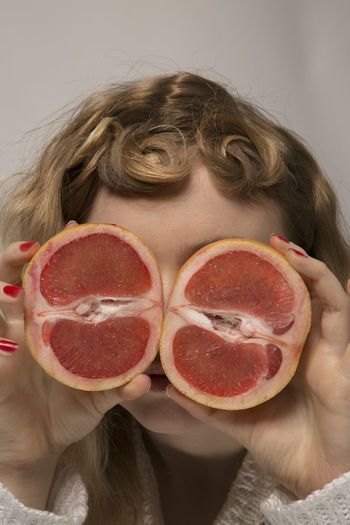 Woman holding citrus fruit in front of her face