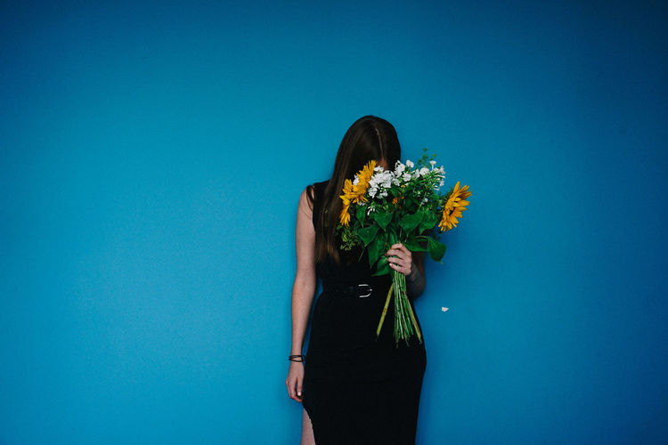 Woman holding flowers against blue background