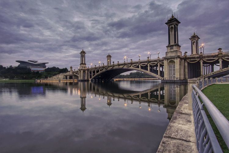 Arch bridge over river against buildings in city
