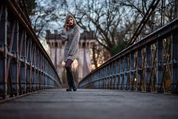 Woman standing on footbridge against bridge