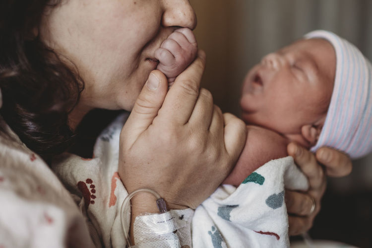 Close up detail of mother in hospital kissing newborn son hand