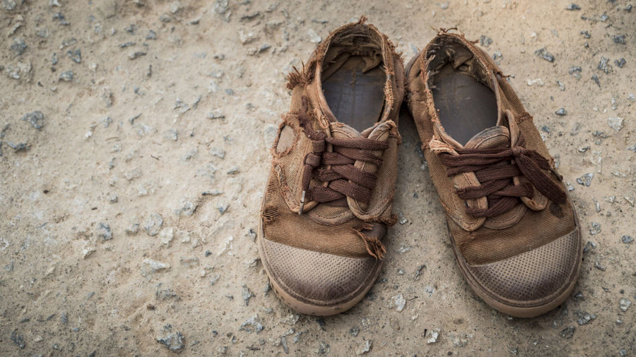 A pair of worn out children shoes on the ground of a rural village in thailand.