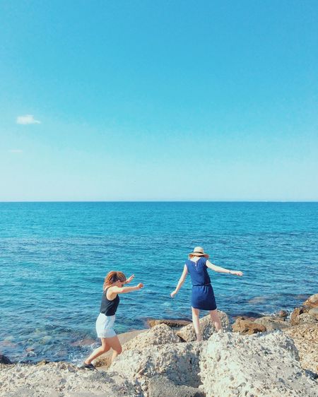 Friends on beach against clear blue sky