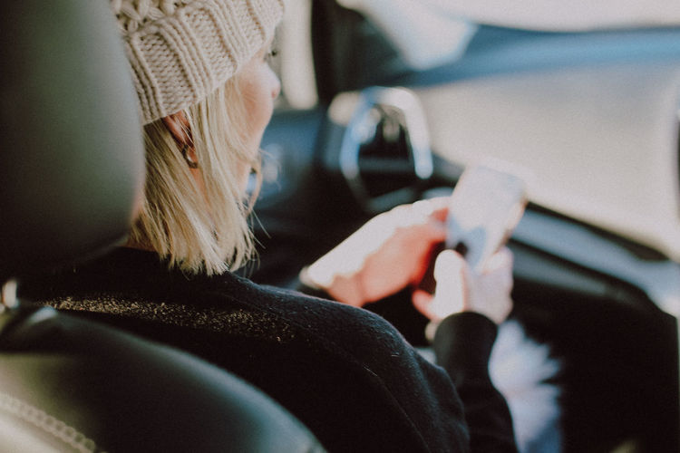 Woman using phone while sitting in car