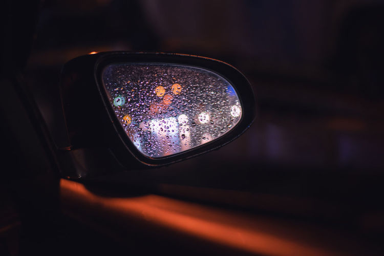 Close-up of water drops on side-view mirror at night