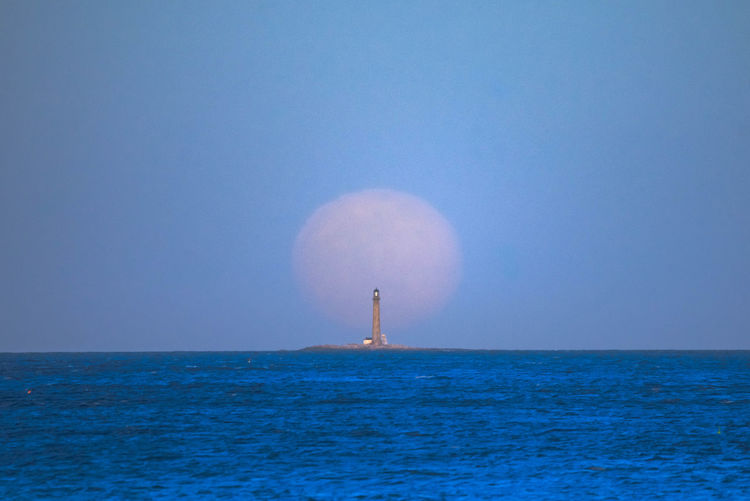 Full moon rising behind the boon island lighthouse