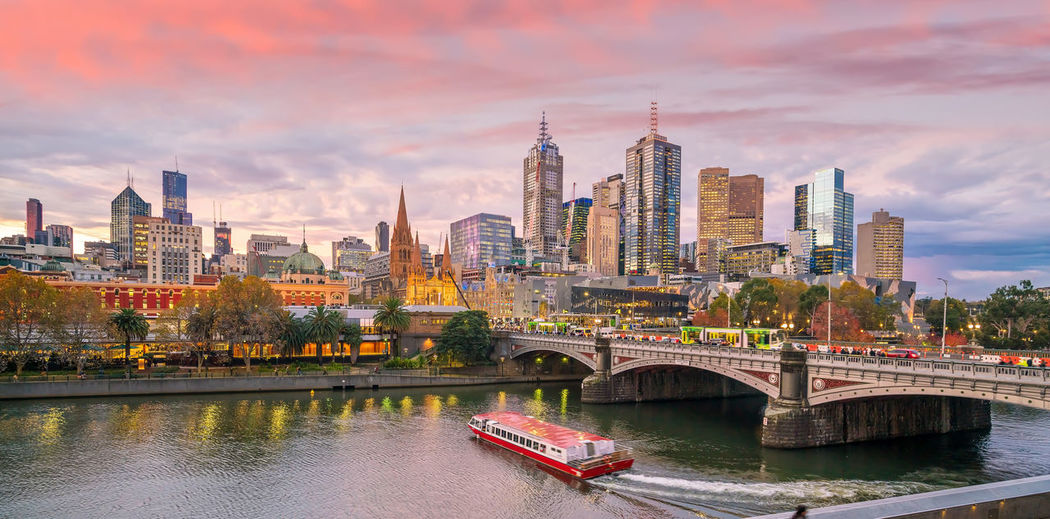 Bridge over river by buildings against sky in city