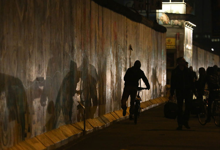 Silhouette man walking on illuminated road