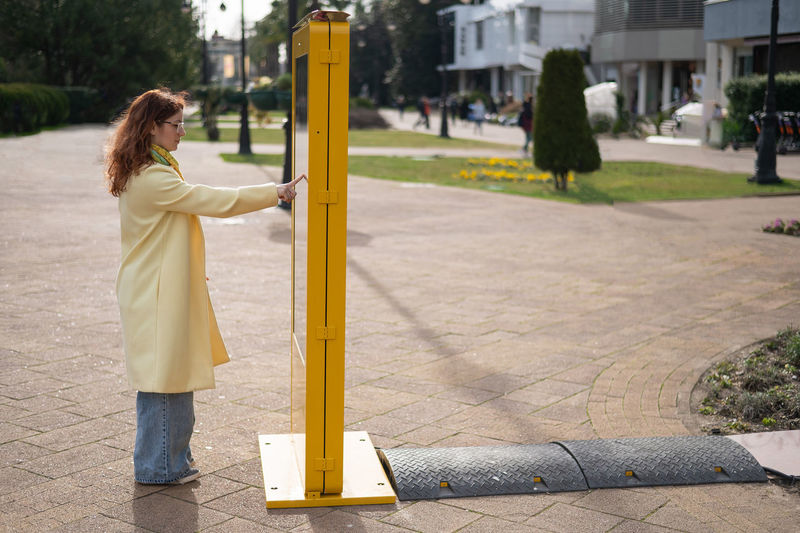 Young woman touching liquid crystal display standing on street