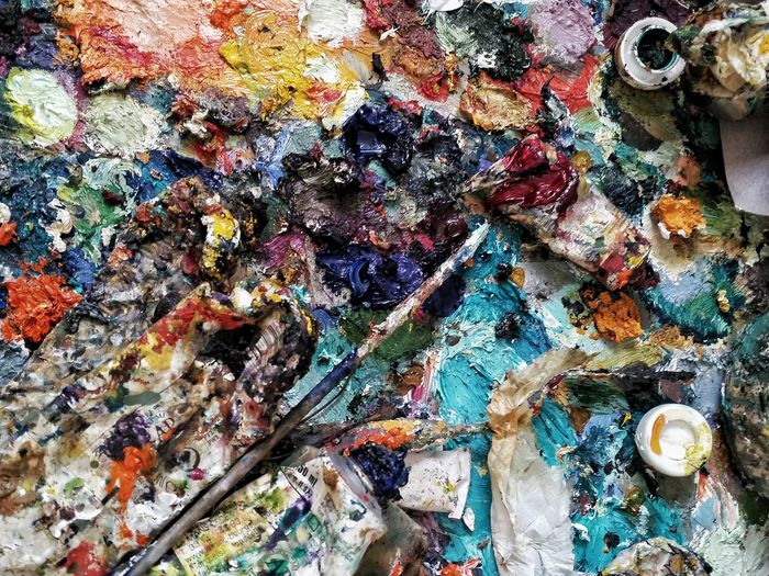 High angle view of paintbrush on colorful messy paint