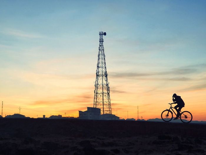 Low angle view of silhouette person riding bicycle against sky during sunset