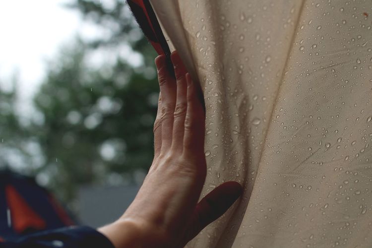 Close-of hand touching wet tent
