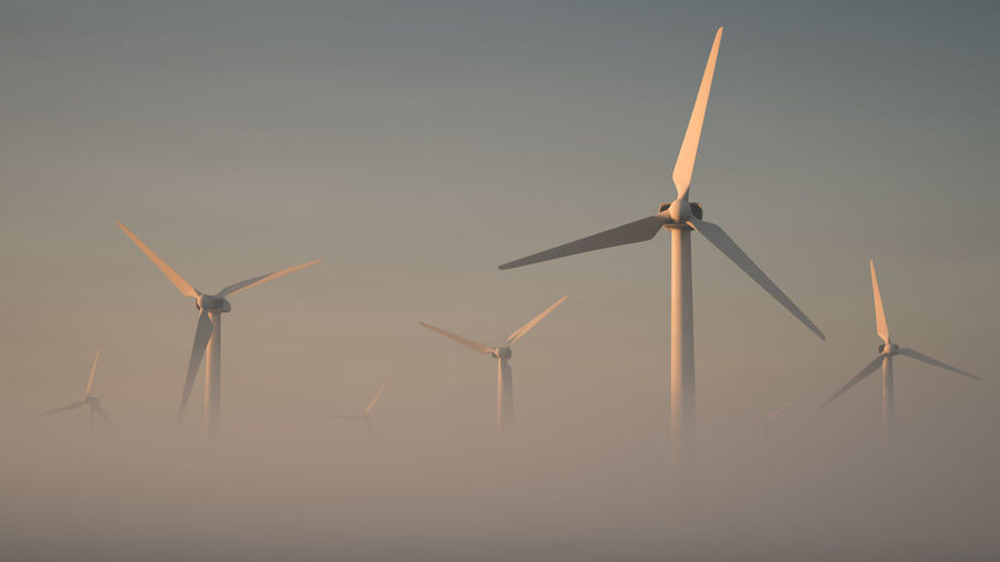 Giant windmills rising out of the mist. theme of green energy. suitable for wallpaper or screensaver