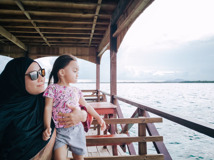 Mother with daughter looking at sea from boat