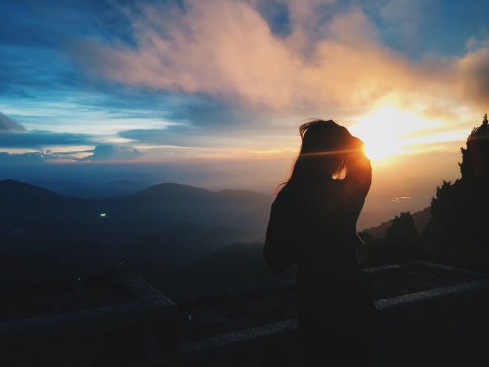 Silhouette woman standing against mountains during sunset