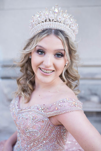 Close-up portrait of smiling beautiful bride wearing crown against wall