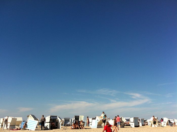 People at beach against blue sky