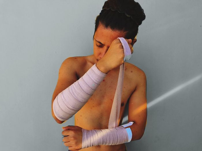Midsection of young man wrapping arms in bandage