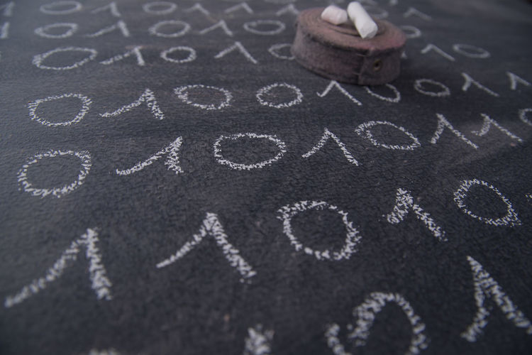 High angle view of chalks amidst drawings on blackboard