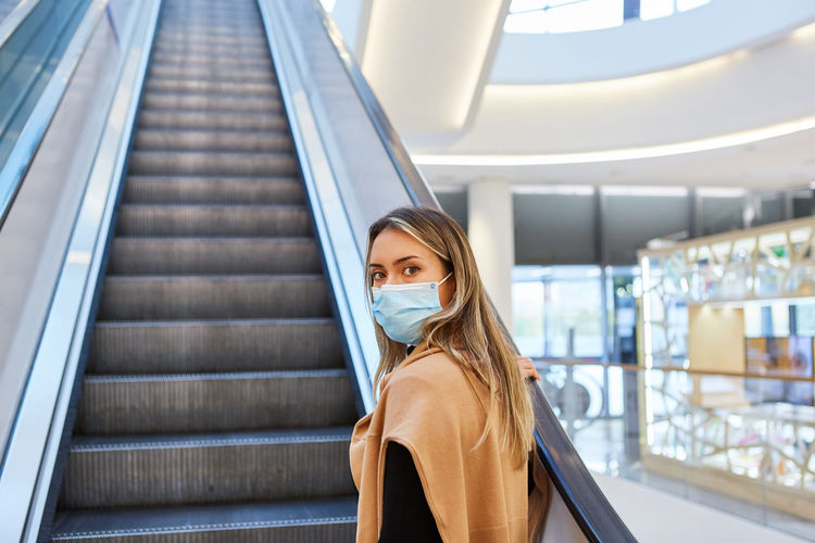 Portrait of beautiful young woman standing against escalator