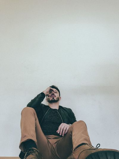 Low angle view of man sitting against wall