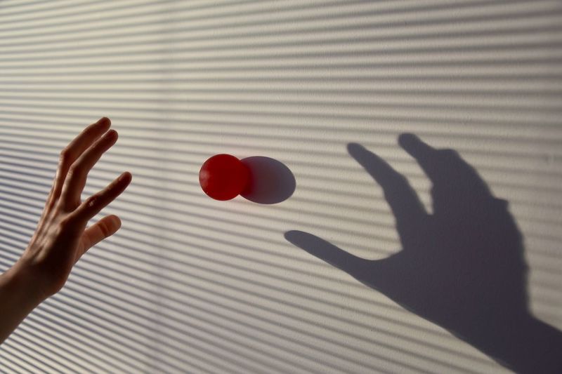 Cropped hand of red ball on floor