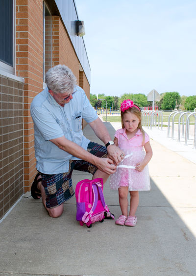 Grandpa wraps a little girl in bubble wrap, in an attempt to keep his grandchild safe at school