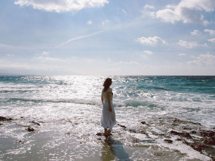 Woman wading in sea against sky