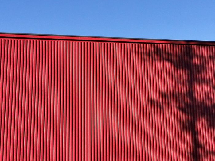 Full frame shot of red wall against blue sky