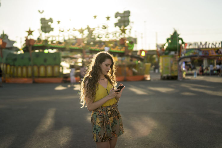 Portrait of young woman standing on mobile phone in city