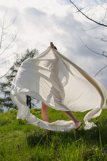 Lady spinning with white cloth in meadow scenic photography