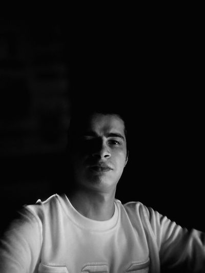 Thoughtful young man looking away against black background