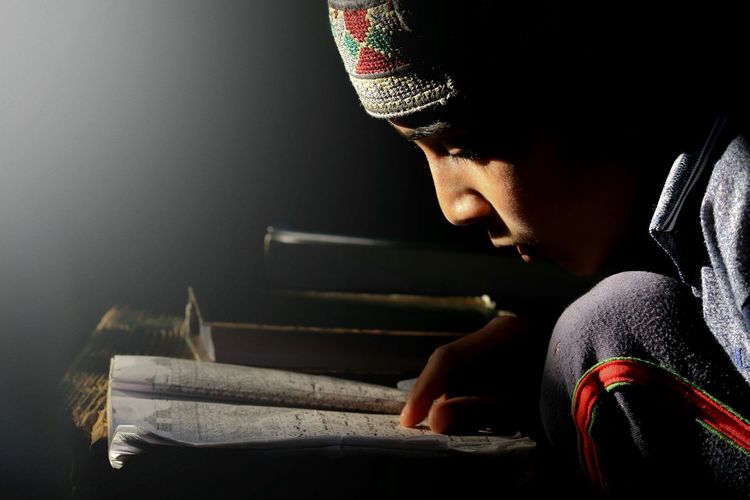 Close-up of boy reading koran