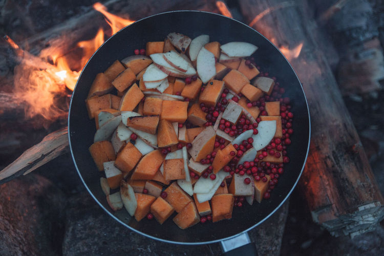 High angle view of frying pan over campfire with vegetables