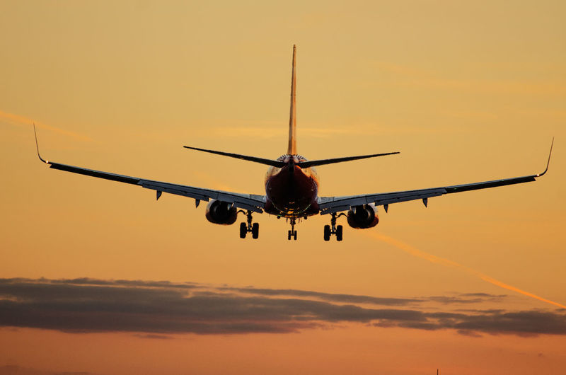 Low angle view of silhouette airplane against sky during sunset