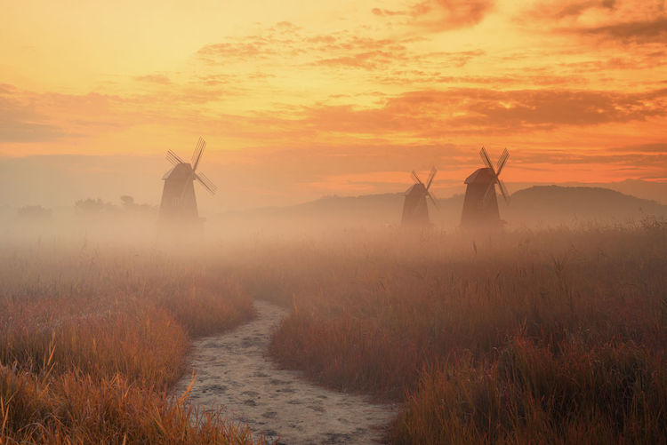 Scenic view of windmills against sky during sunset