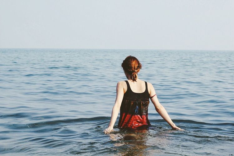 Rear view of woman standing in sea